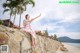 A woman sitting on a stone wall on the beach.