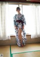 A woman in a kimono standing in front of a window.