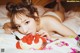 A woman laying on a bed eating a strawberry cake.