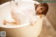 A woman in a white shirt is sitting in a bathtub.