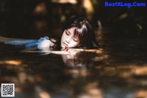 A woman in a blue dress is floating in the water.