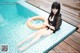 A woman sitting on the edge of a swimming pool with an inflatable ring.