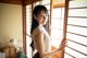 A woman standing in front of a window with blinds.