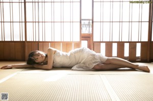 A woman laying on the floor in front of a window.