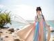 A woman in a colorful dress standing on a beach.