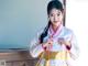 A woman in a white and pink hanbok is posing for a picture.