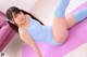 A woman in a blue tank top and blue socks is doing a yoga pose.