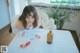 A woman sitting at a table with a glass of water and strawberries.