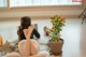 A woman sitting on the floor next to a potted plant.