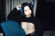 A woman sitting on a blue chair wearing a black shirt and fishnet stockings.